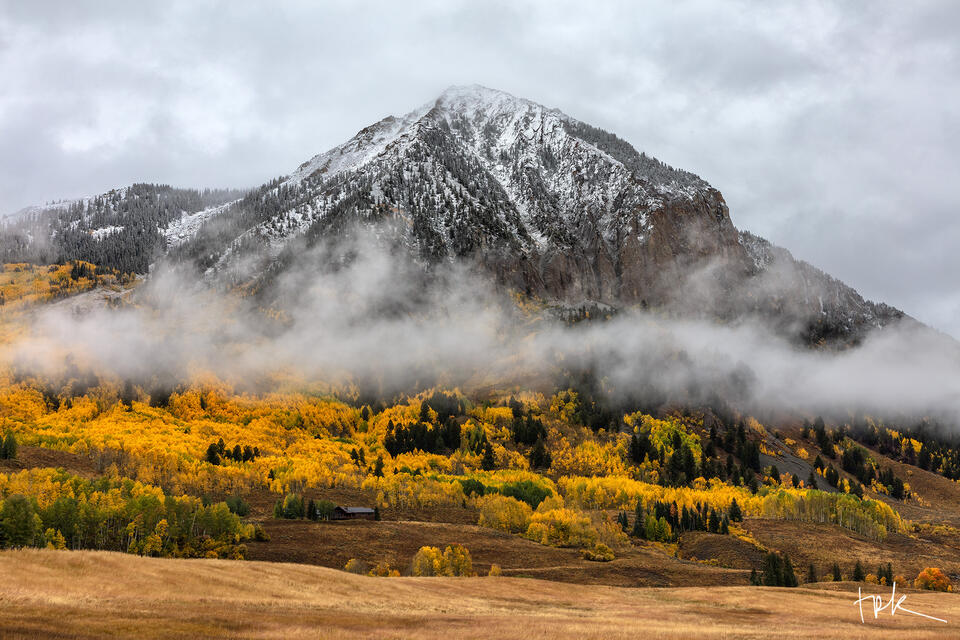 Limited edition print of Colorado’s Crested Butte ringed by low clouds and covered with aspens in peak yellow fall color.