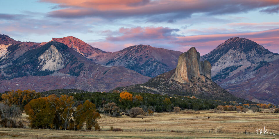 Limited edition panoramic print of a Colorado’s Needle Rock under a lavender autumn sunset with the peaks of the West Elk Mountains in the background.