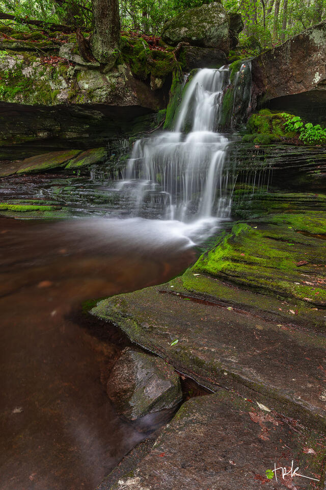 Limited edition print of a small Connecticut waterfall in the lush spring woodland with moss covering the rock steps on either side.